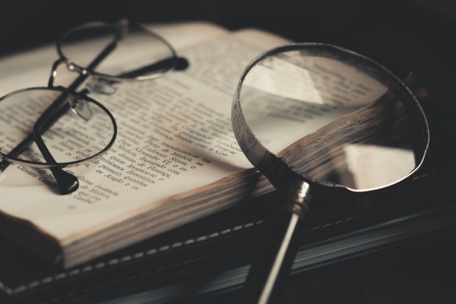 Une loupe et une paire de lunettes posées sur un livre ouvert