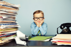 Enfant à l'air blasé entouré de documents à traiter 