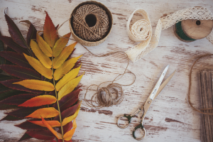 Photo de feuilles d'arbre et de matériel de couture posés sur une planche