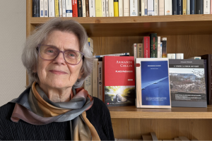 Photo de l'autrice Armande Collin devant ses 3 livres posés sur une bibliothèque